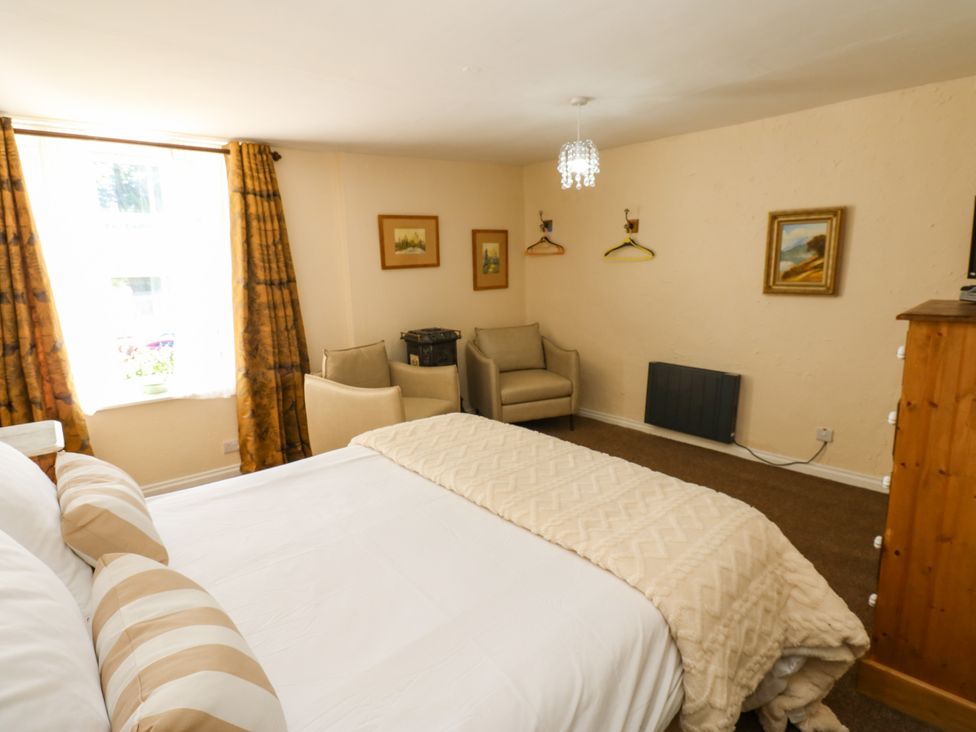 A bedroom with a bed and chairs at Arch Mews Cottage Middleton-In-Teesdale