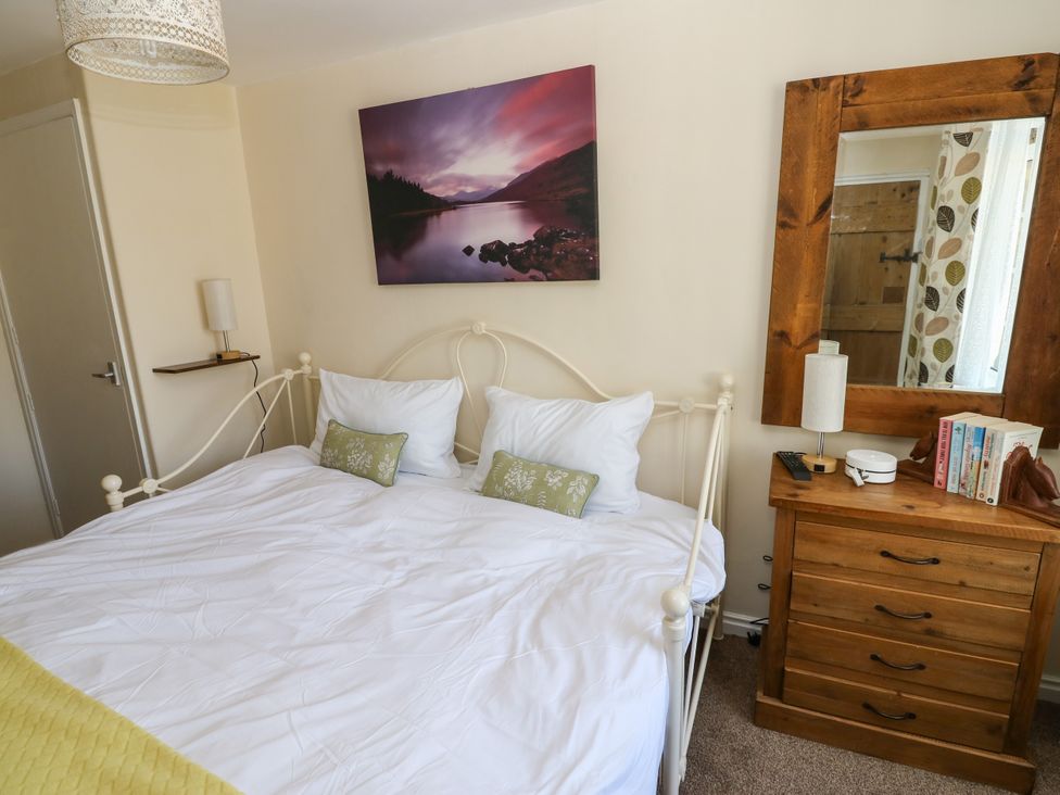A bedroom with a bed, nightstand, mirror and wall art at Arch Mews Cottage Middleton-In-Teesdale