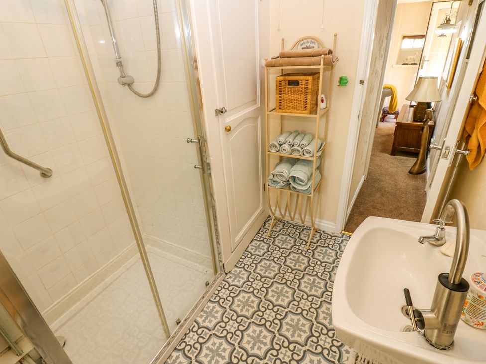 A bathroom with a shower, sink, and towel storage at Arch Mews Cottage Middleton-In-Teesdale