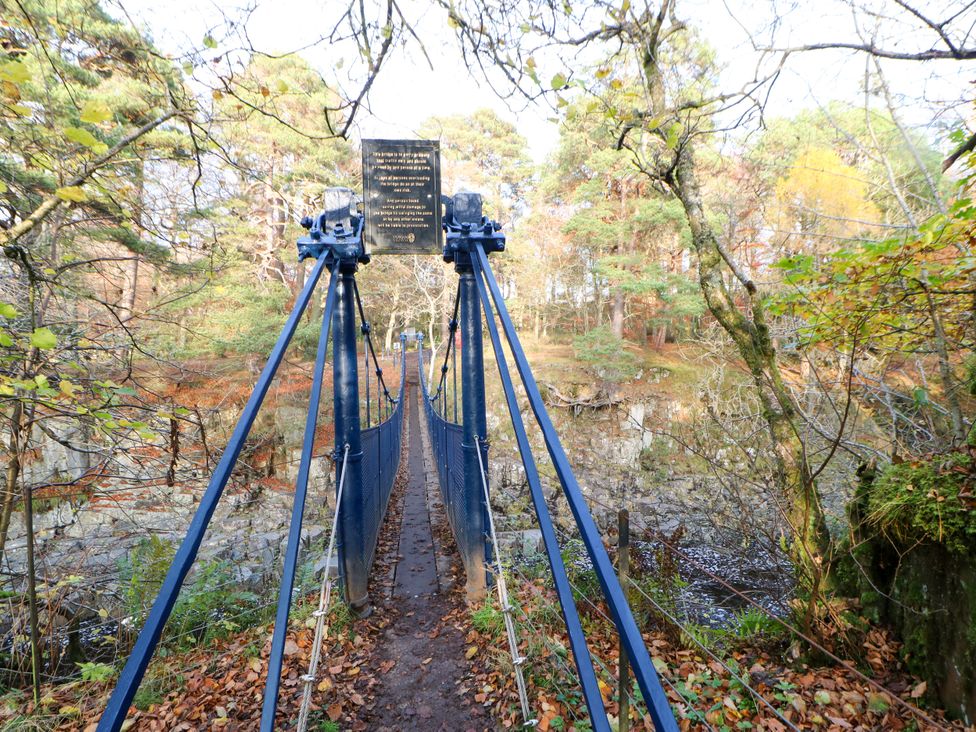 A suspension bridge with trees around and a plaque at Arch Mews Cottage Middleton-In-Teesdale
