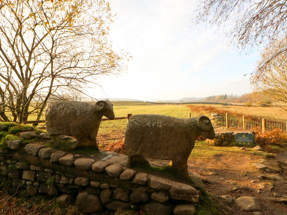 Stone sheep sculptures on a dry stone wall in a field