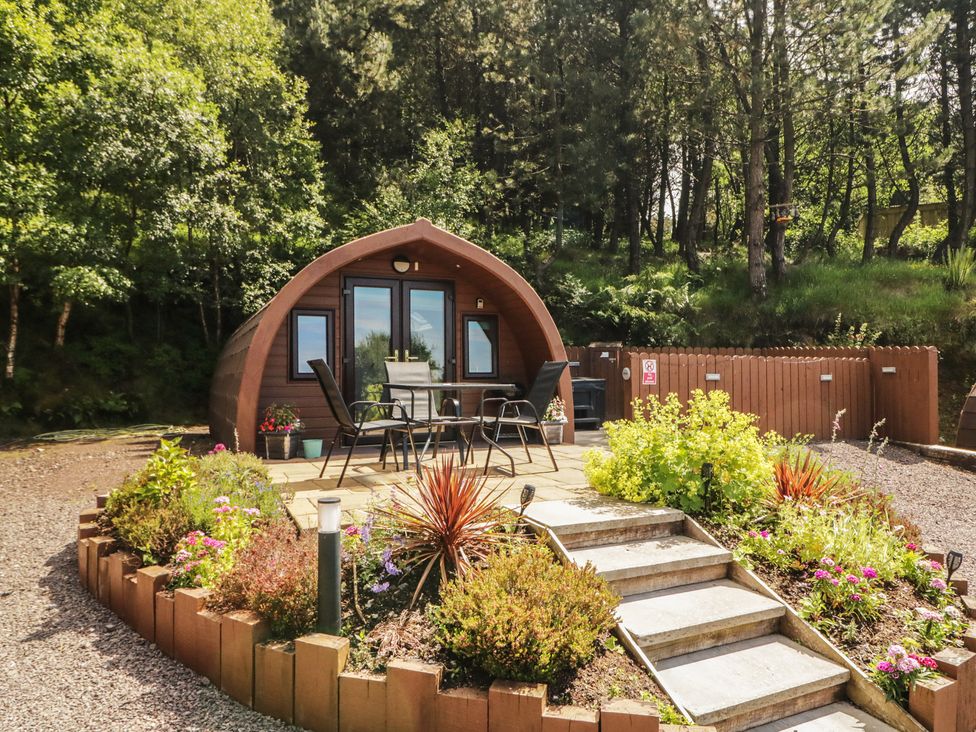 An outdoor area with a glamping pod and seating at Gortin Glen Glamping Pod 1