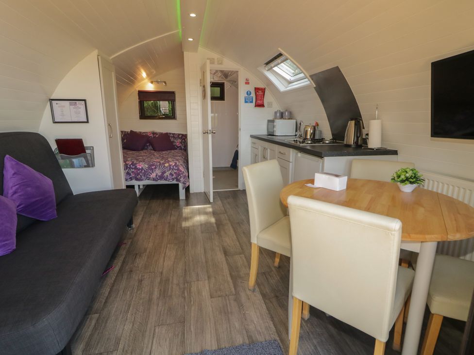 A living room with a sofa bed and dining area at Gortin Glen Glamping Pod 1