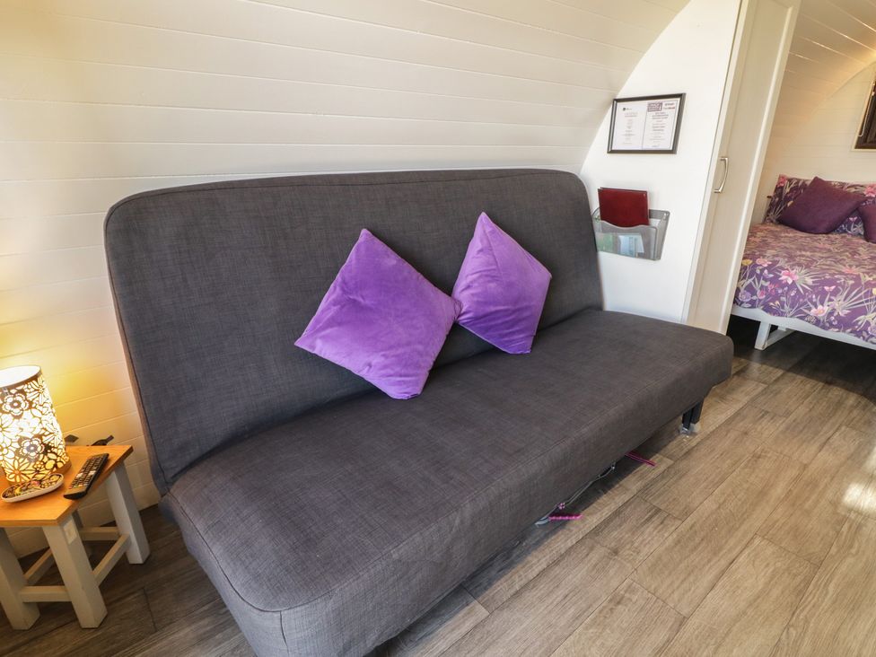 A living room with a sofa and table at Gortin Glen Glamping Pod 1