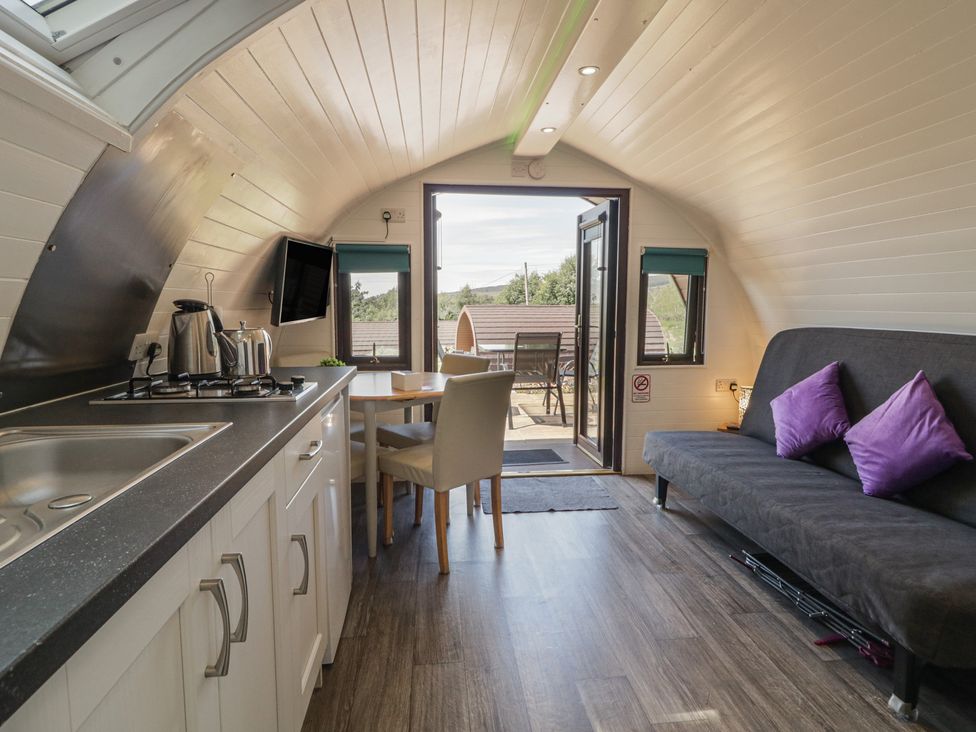 A kitchen with a table and chairs and a sofa at Gortin Glen Glamping Pod 1