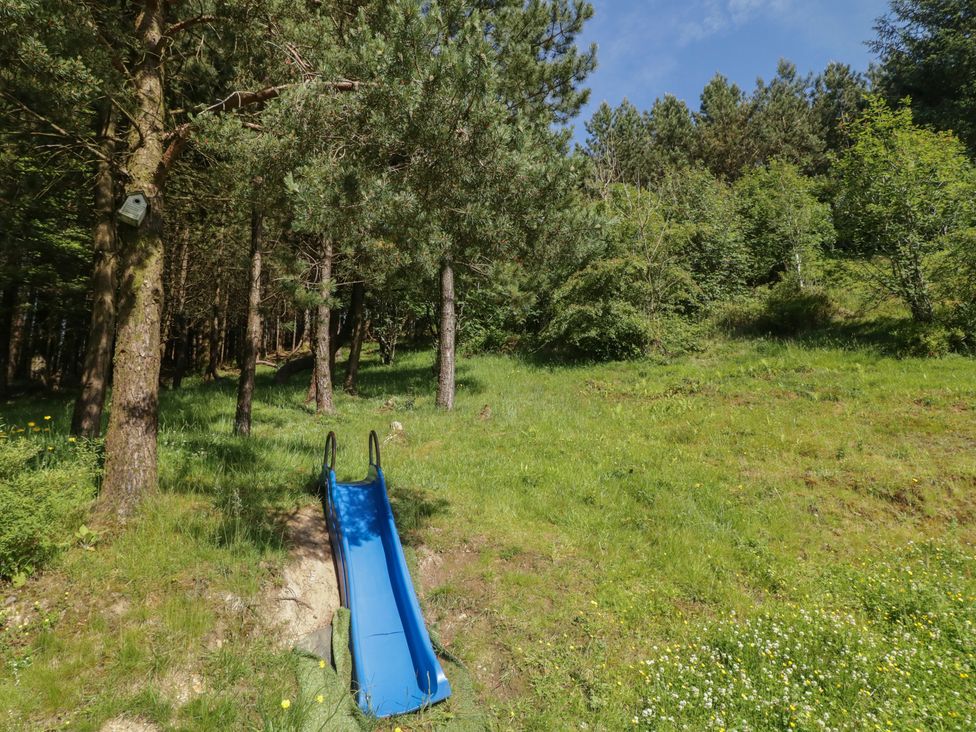 A slide in a grassy area surrounded by trees at Gortin Glen Glamping Pod 1
