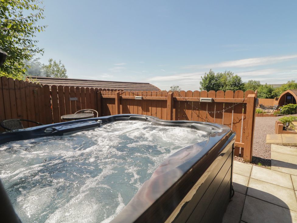 An outdoor area with a hot tub and chairs at Gortin Glen Glamping Pod 1