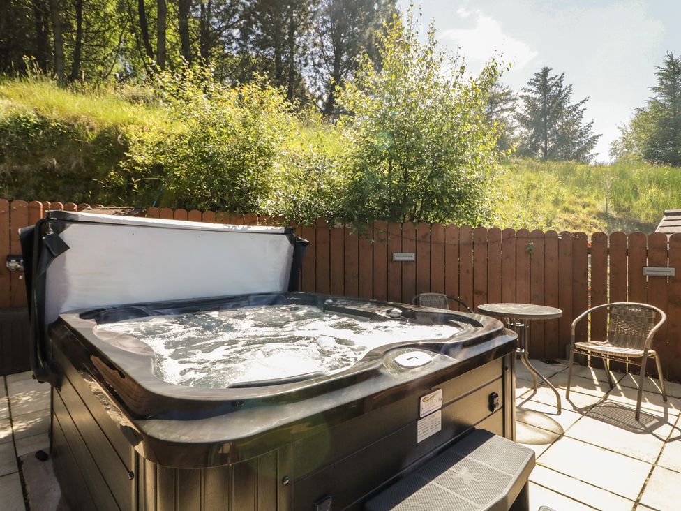 An outdoor space with a hot tub and seating area at Gortin Glen Glamping Pod 1
