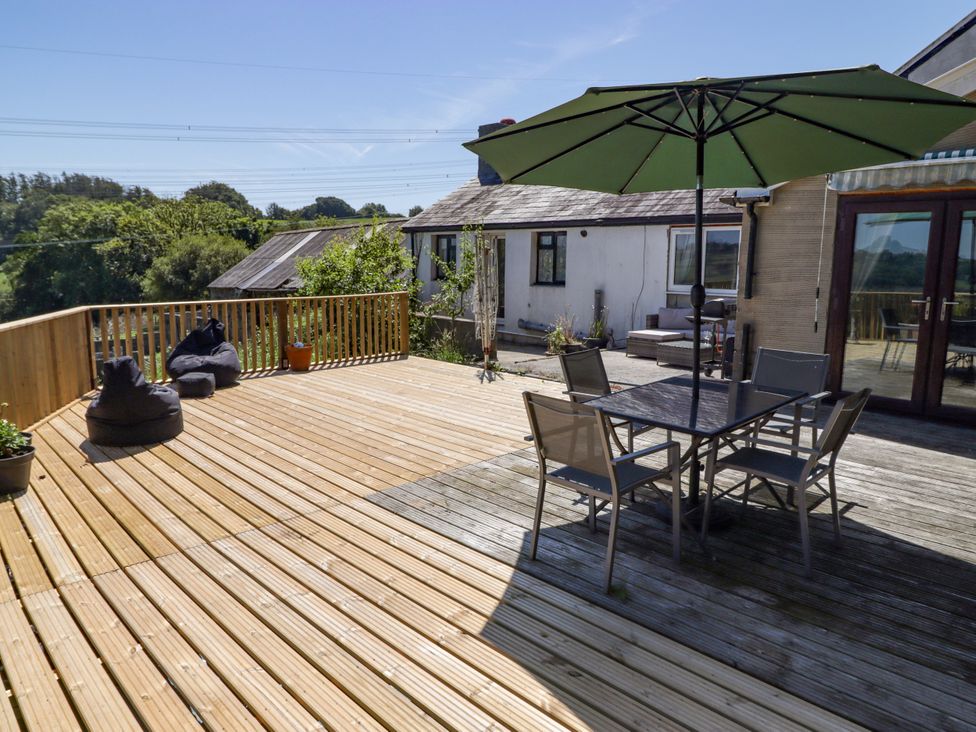 An outdoor area with a deck, table, chairs and umbrella at Farm Cottage in 
