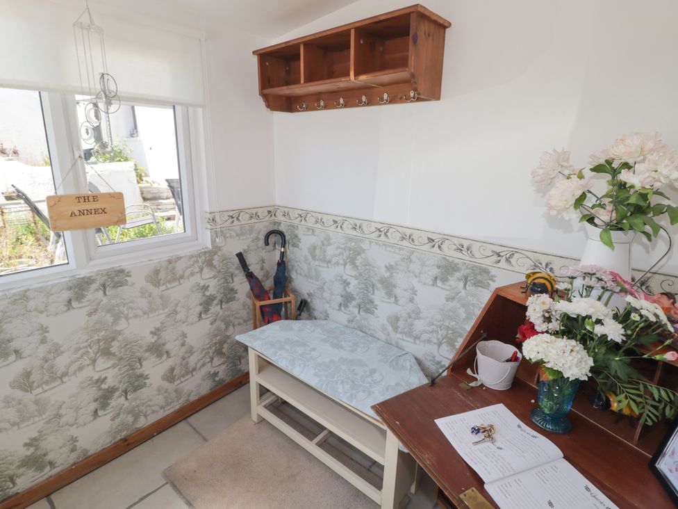 An entryway with a bench and flowers at Farm Cottage