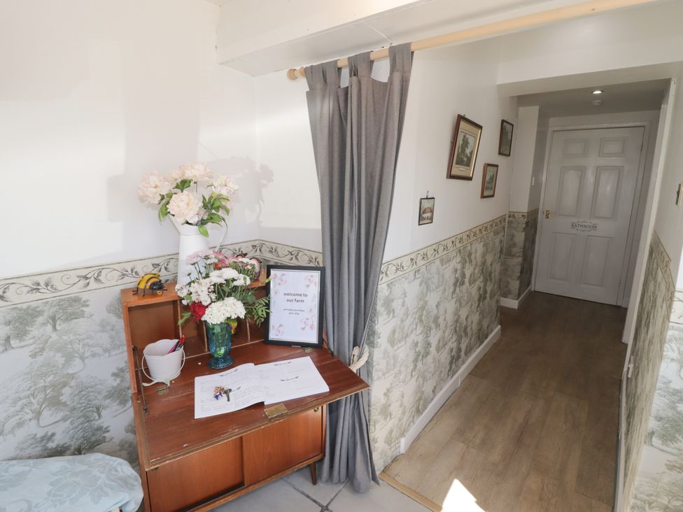A hallway with a table and flowers at Farm Cottage