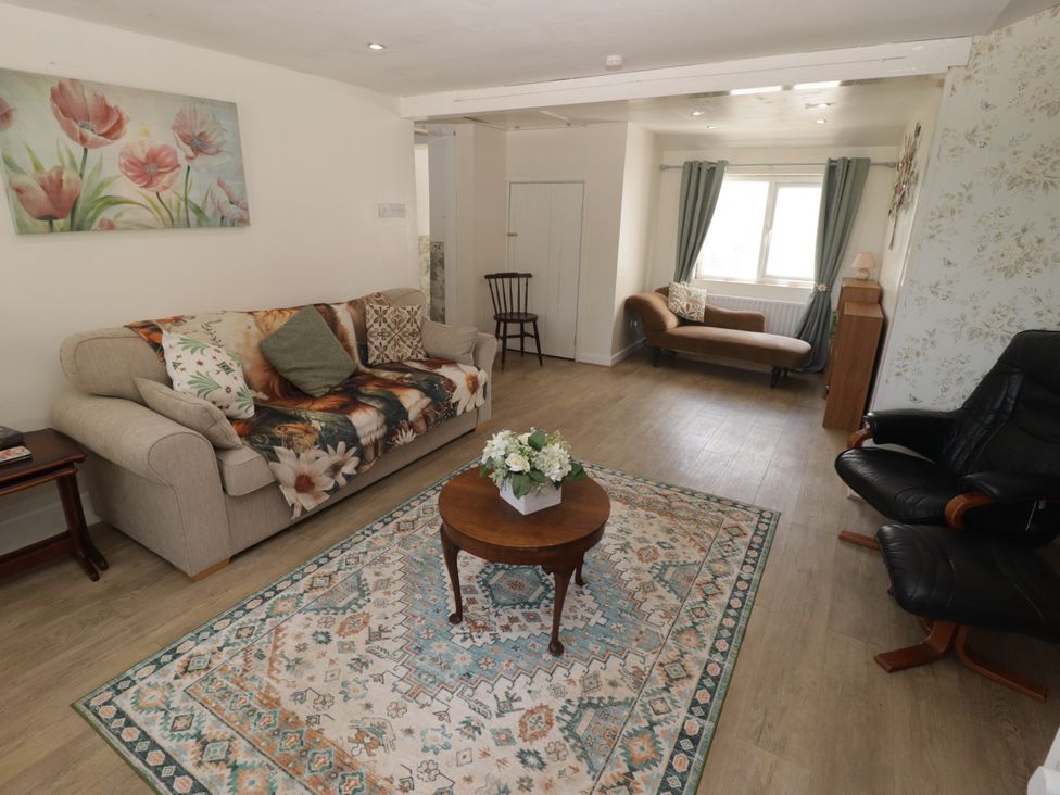 A living room with a sofa, armchair, and coffee table at Farm Cottage 