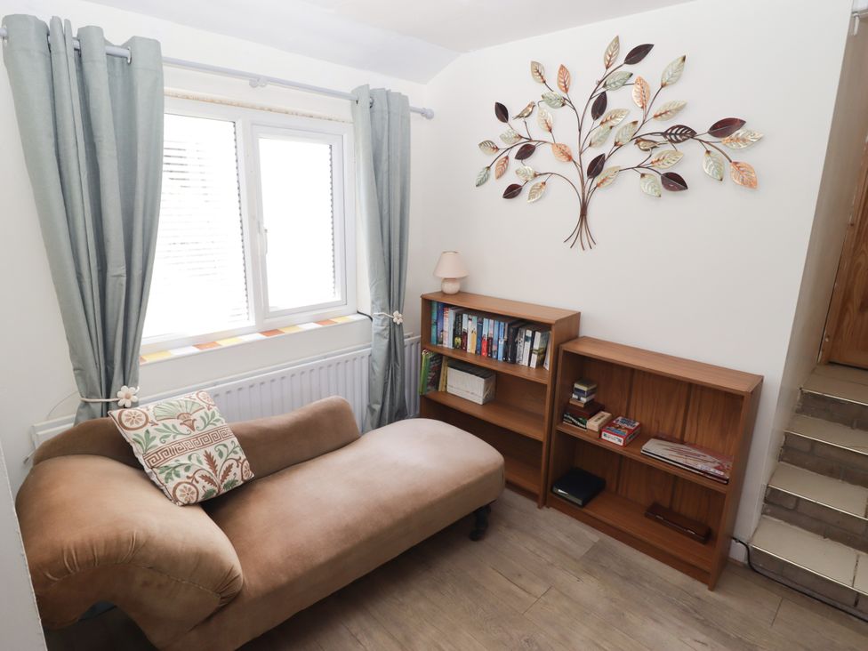 A snug with a window, seating area and bookshelf at Farm Cottage