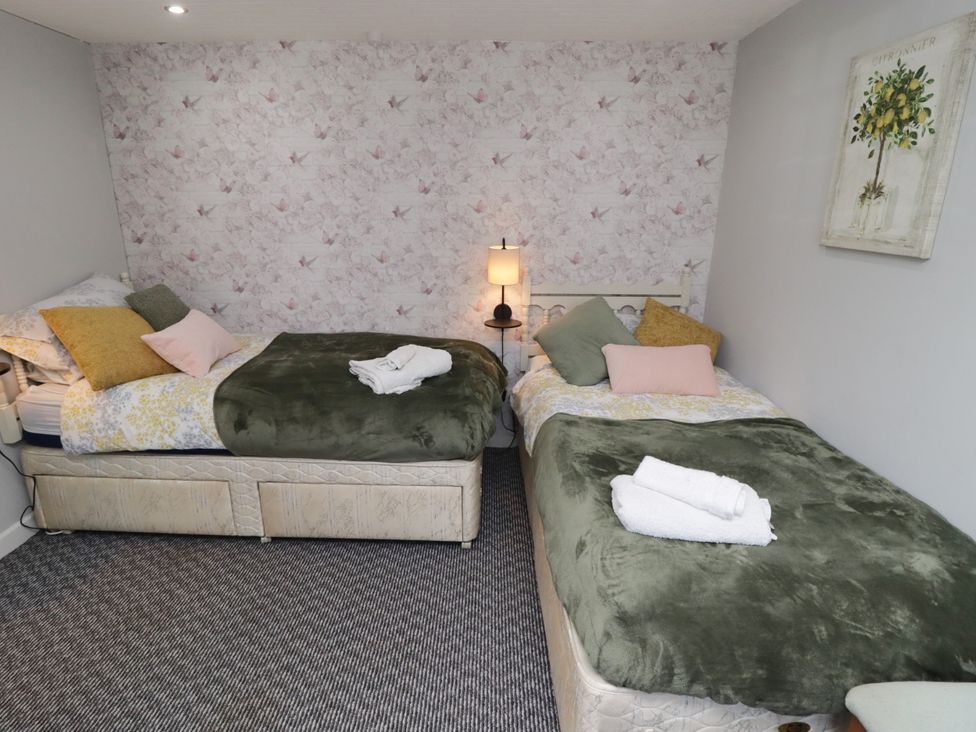 A bedroom with two beds and a lamp at Farm Cottage