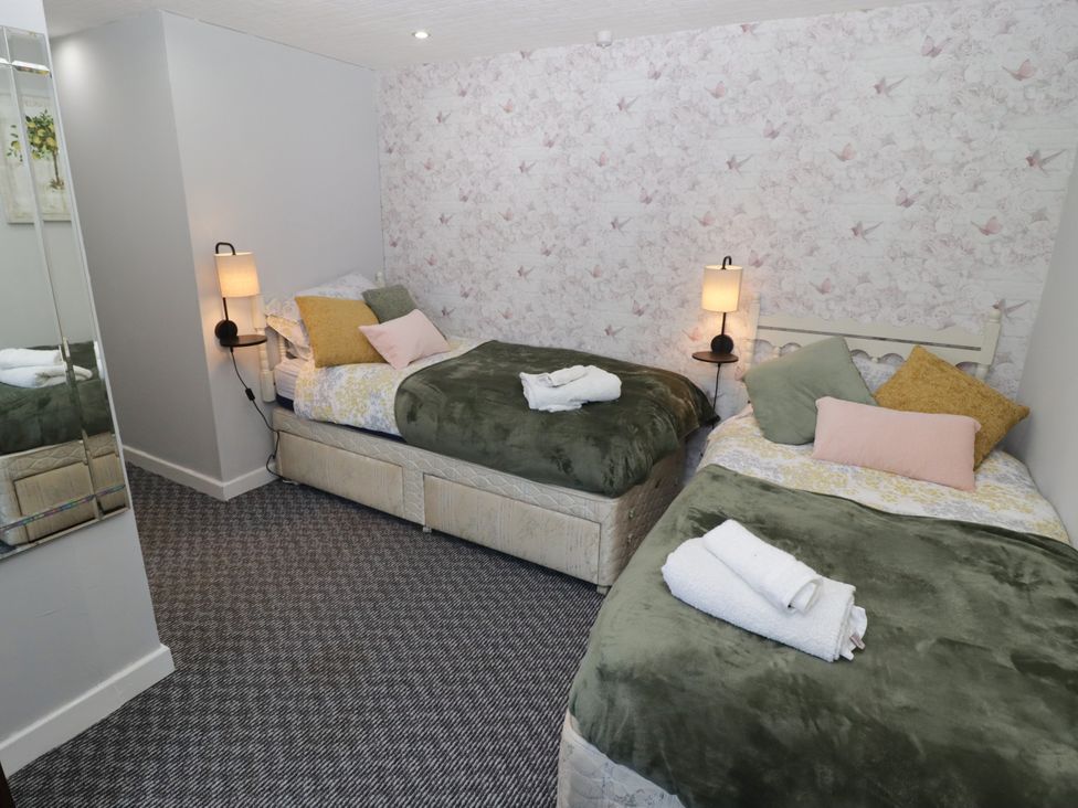 A bedroom with two beds and a mirror at Farm Cottage