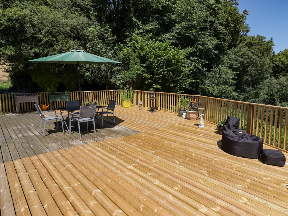 An outdoor deck with a table, chairs, and an umbrella at Farm Cottage