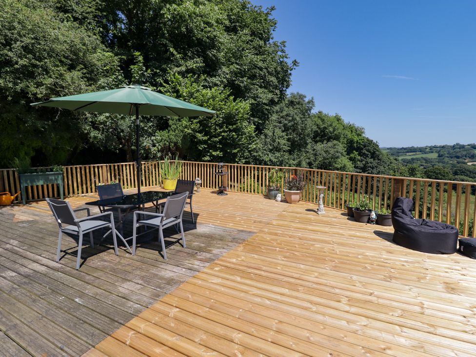 A deck with a table and chairs under an umbrella at Farm Cottage