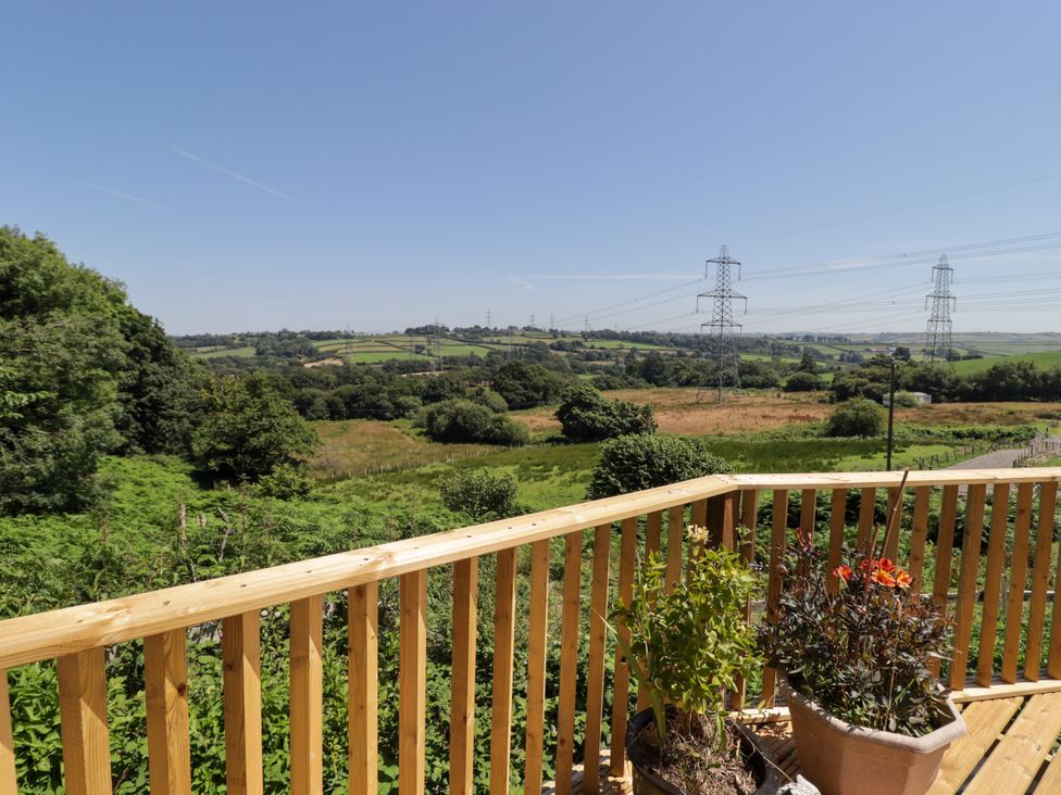 A view of fields and power lines from a wooden balcony at Farm Cottage