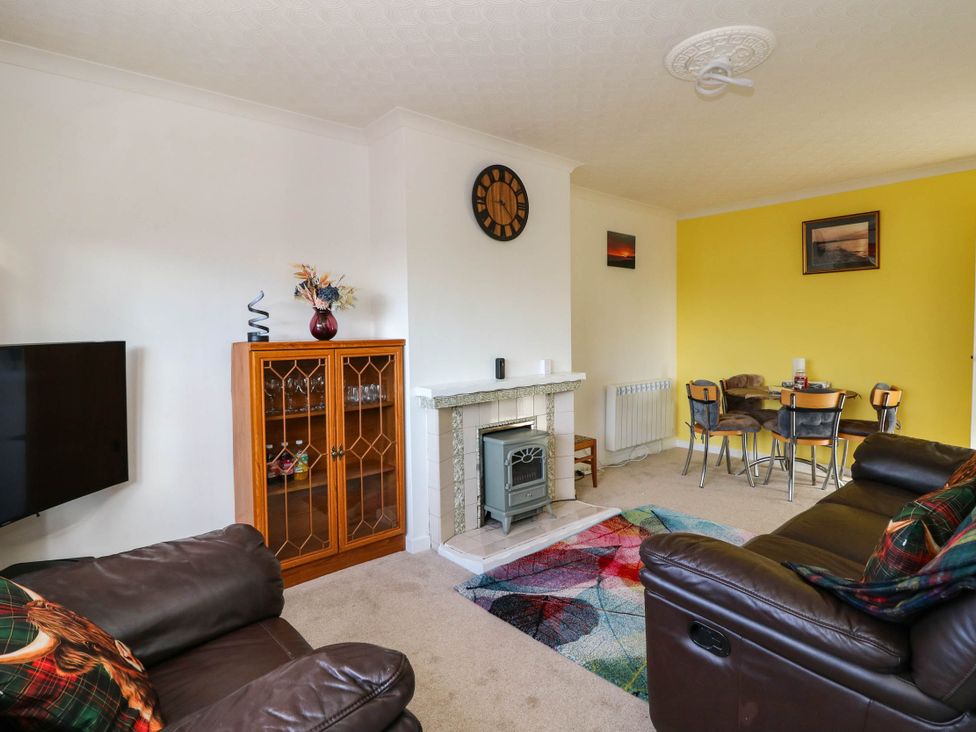 A living room with a sofa, television, and dining table at 7 Creag Ruadh in Laxdale near Stornoway