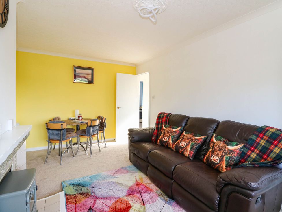 A living room with a sofa and dining table at 7 Creag Ruadh in Laxdale near Stornoway