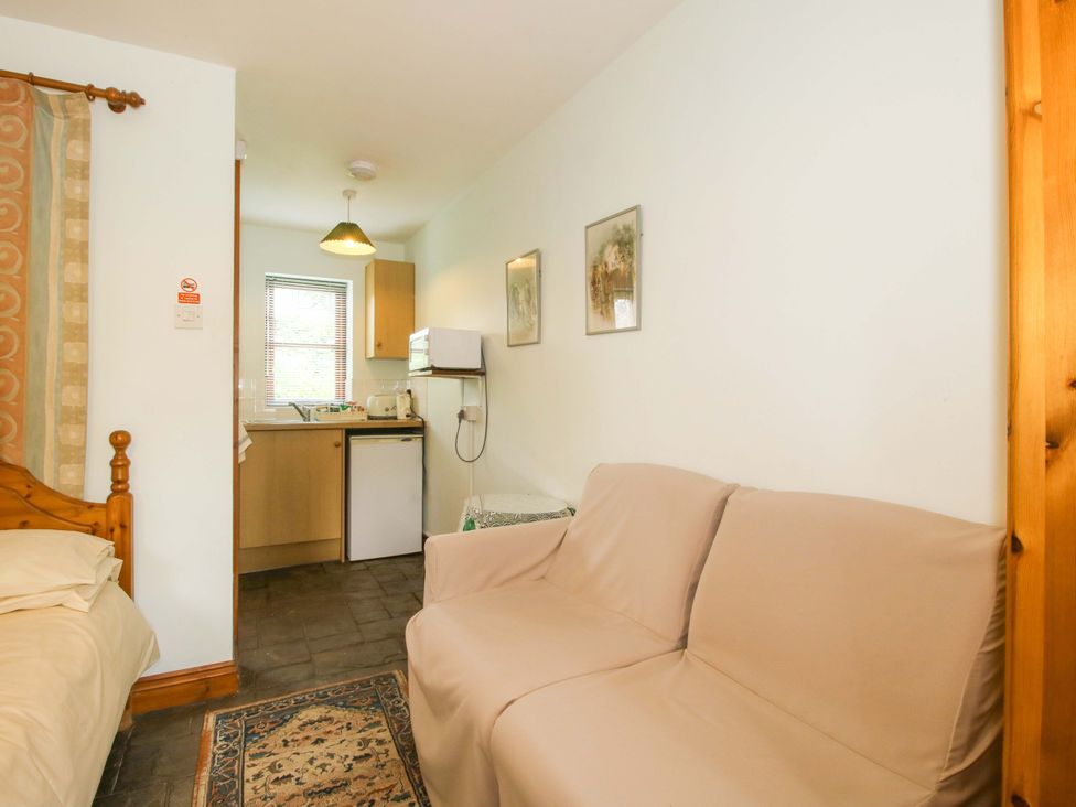 A kitchen area with a sofa and refrigerator at Apartment 2 in Lydbury North