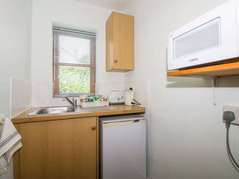 A kitchen with a sink, microwave, and fridge at Apartment 2 in Lydbury North