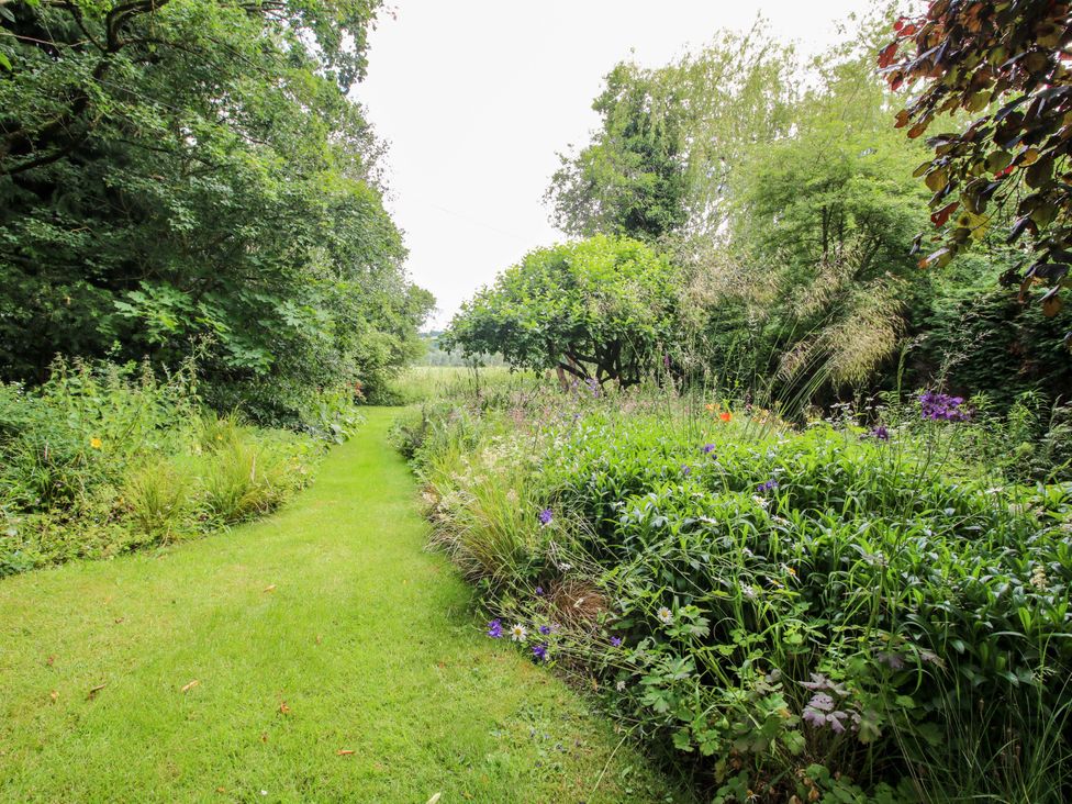 A garden with a path surrounded by flowers and trees at Apartment 2 in Lydbury North