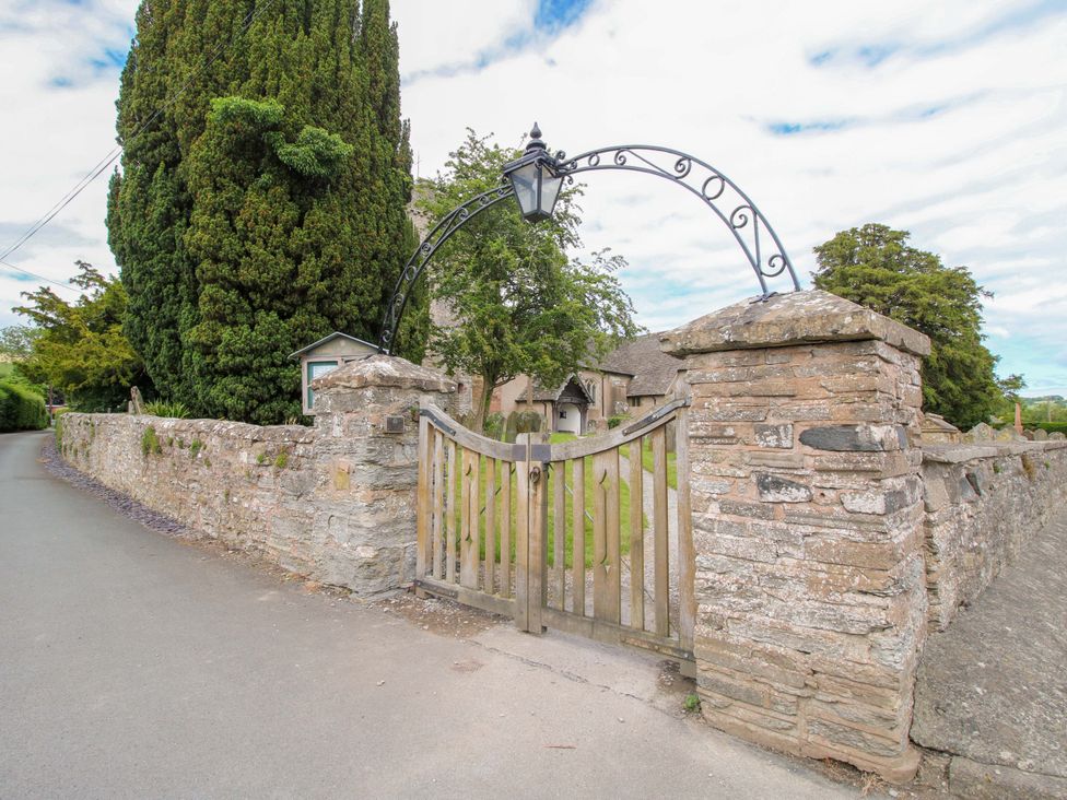 An entrance with a wooden gate and stone wall at Apartment 2 in Lydbury North