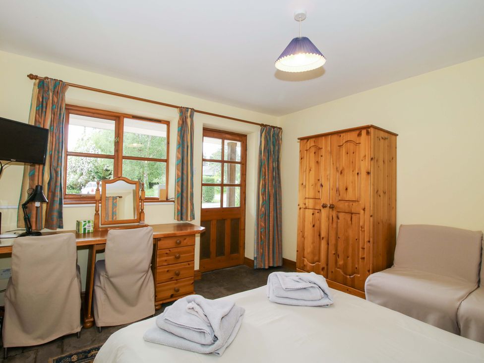 A bedroom with a bed, desk, and wooden wardrobe at Apartment 3 in Lydbury North