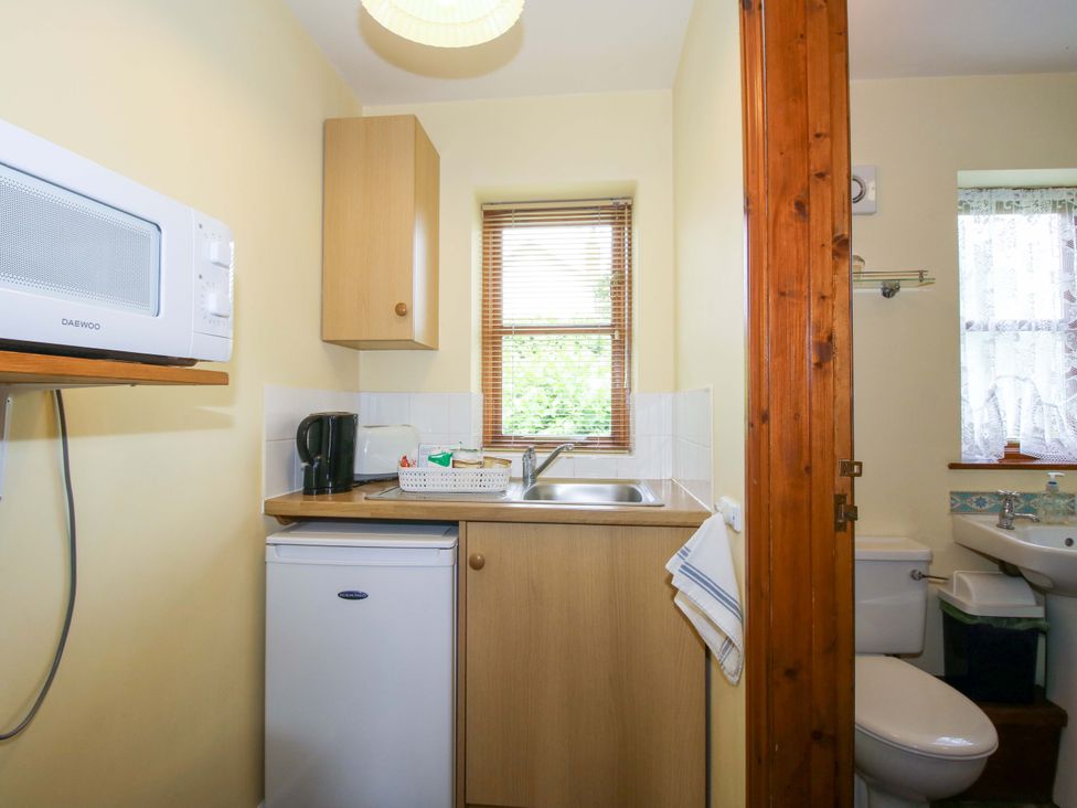 A kitchen with a microwave, sink, and refrigerator at Apartment 3 in Lydbury North