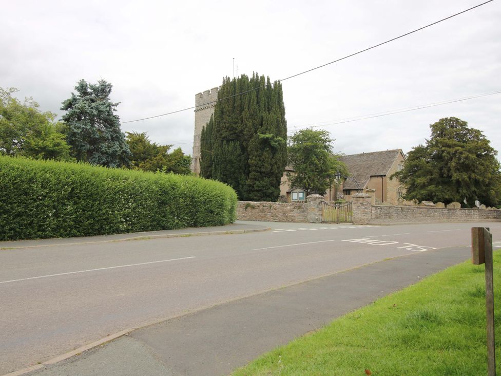 A building with a tower and trees near a road at Apartment 3 in Lydbury North