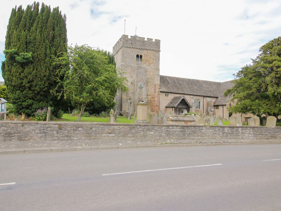 A church with gravestones and trees at Apartment 3 in Lydbury North