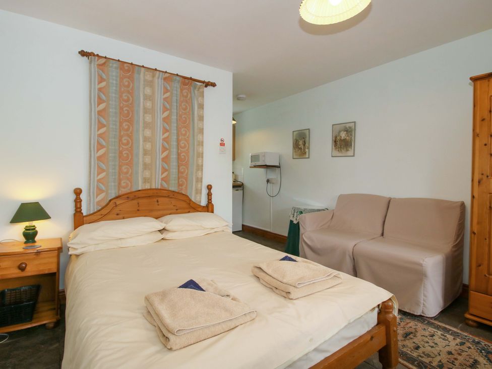 A bedroom with a bed and a seating area at Apartment 4 in Lydbury North