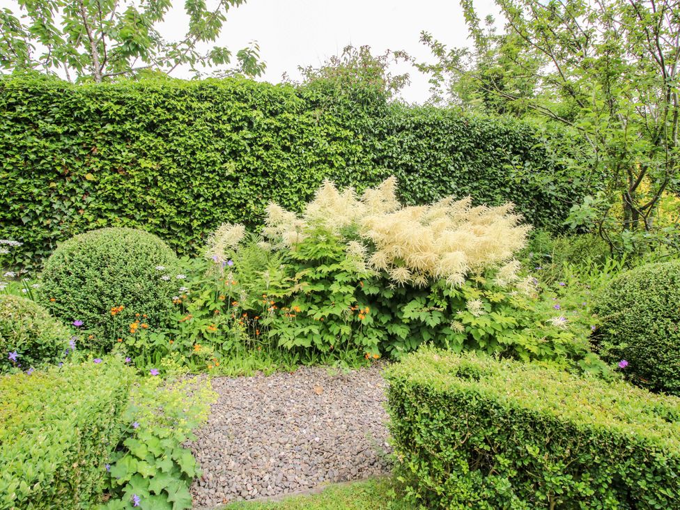 A garden with bushes, hedges, and gravel at Apartment 4, Lydbury North