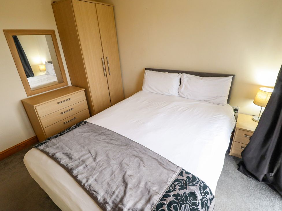 A bedroom with a bed, wardrobe, and mirror at Holiday Cottage 1 in Skegness