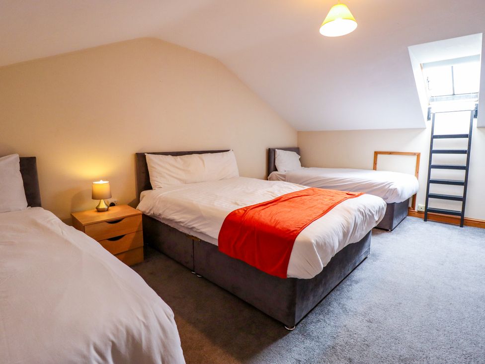 A bedroom with three beds and a lamp at Holiday Cottage 1 in Skegness