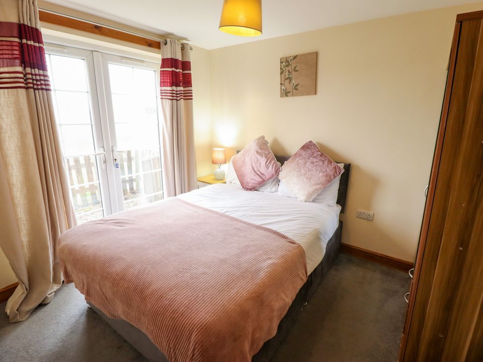 A bedroom with a bed and curtains at Holiday Cottage 2 in Skegness