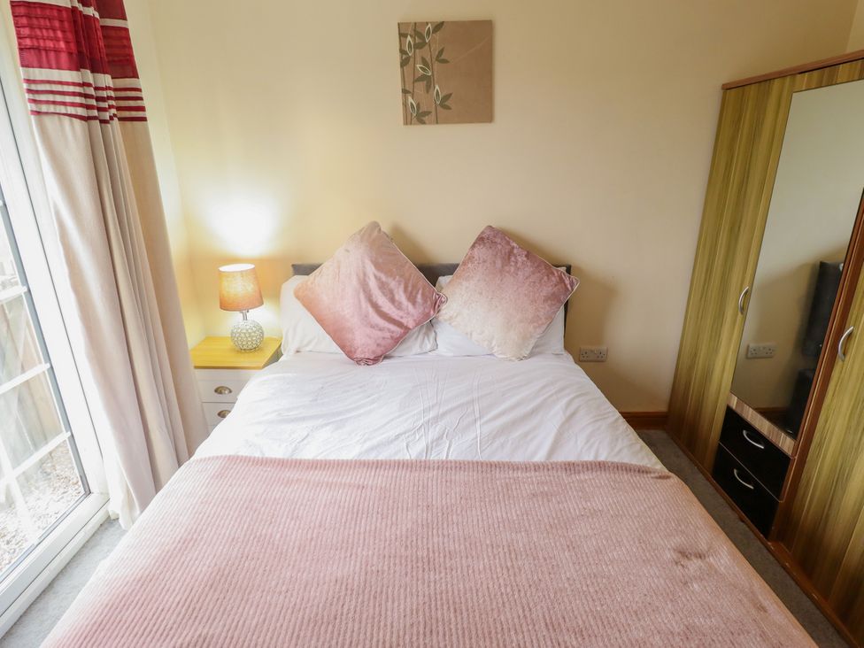 A bedroom with a bed and wardrobe at Holiday Cottage 2 in Skegness