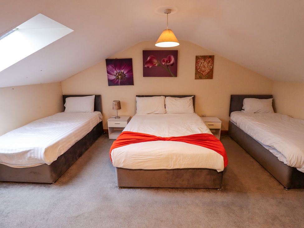 A bedroom with three beds and a nightstand at Holiday Cottage 2 Skegness