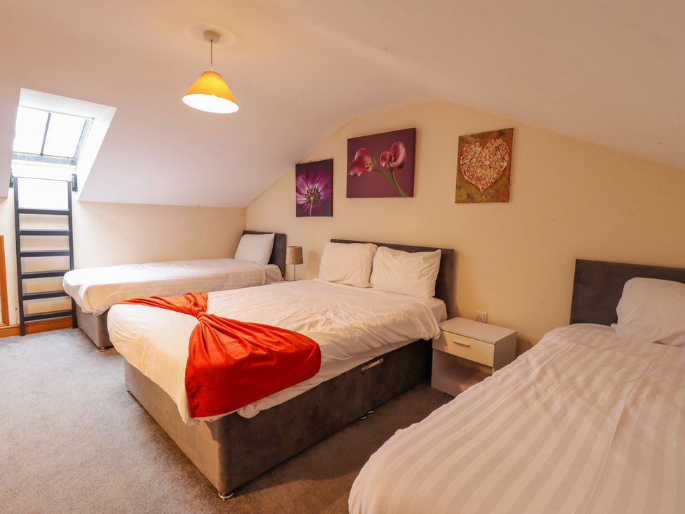 A bedroom with three beds and a staircase at Holiday Cottage 2 in Skegness