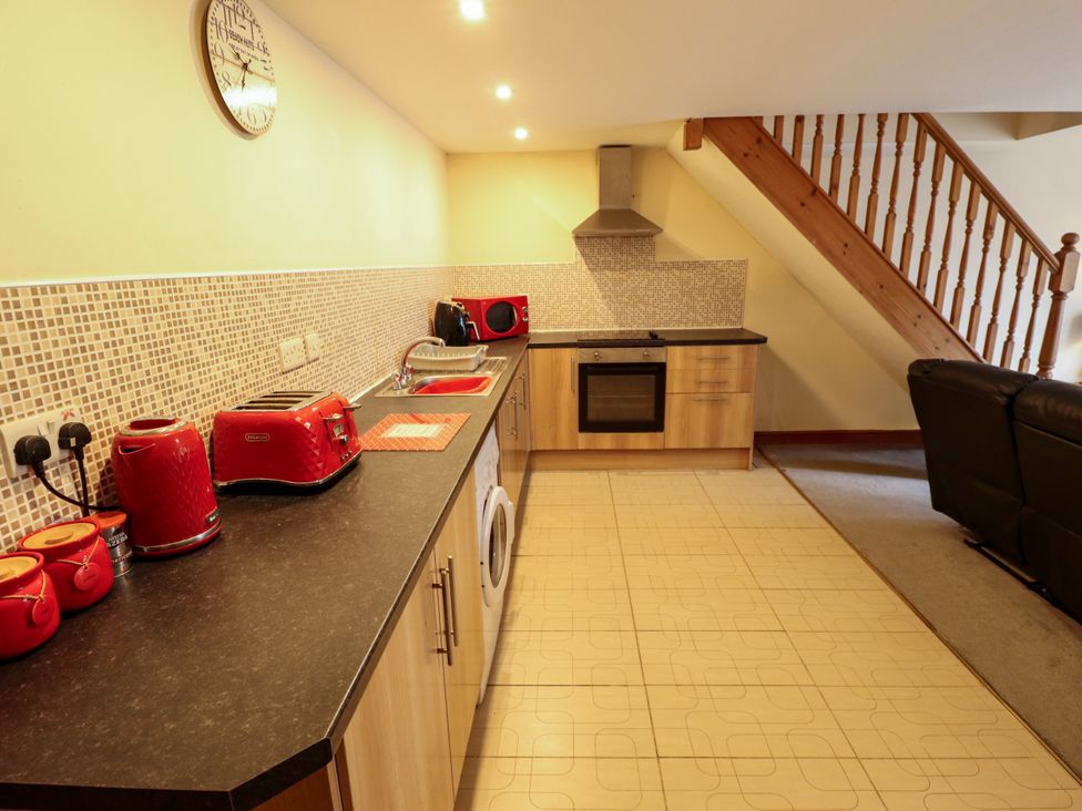 A kitchen with appliances and a staircase at Holiday Cottage 3 in Skegness