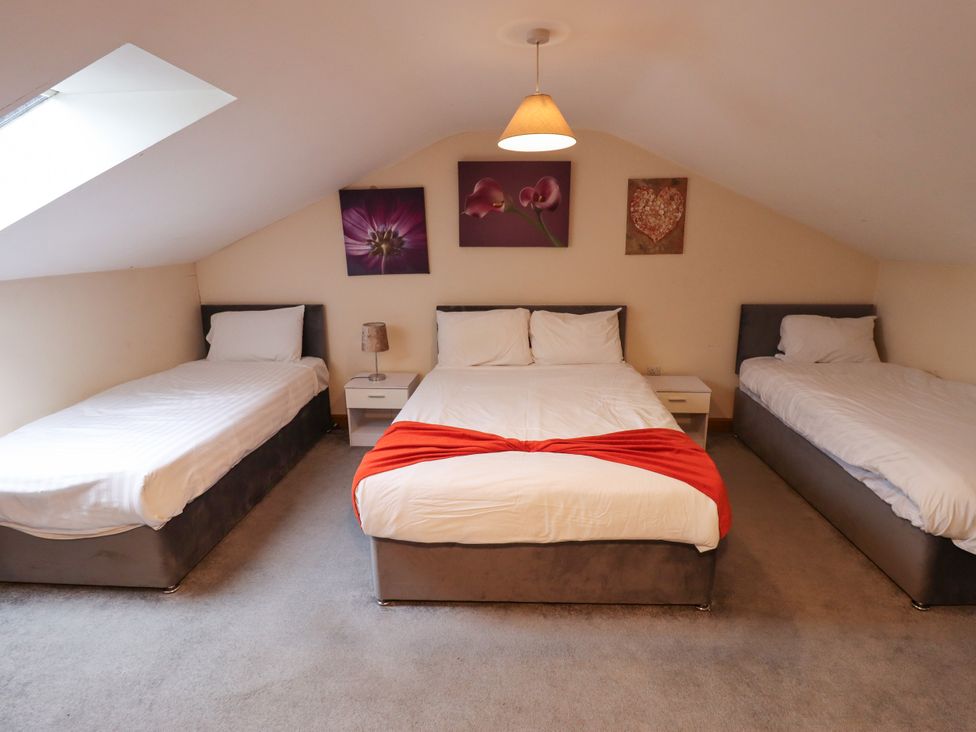 A bedroom with three beds and wall art at Holiday Cottage 3 in Skegness