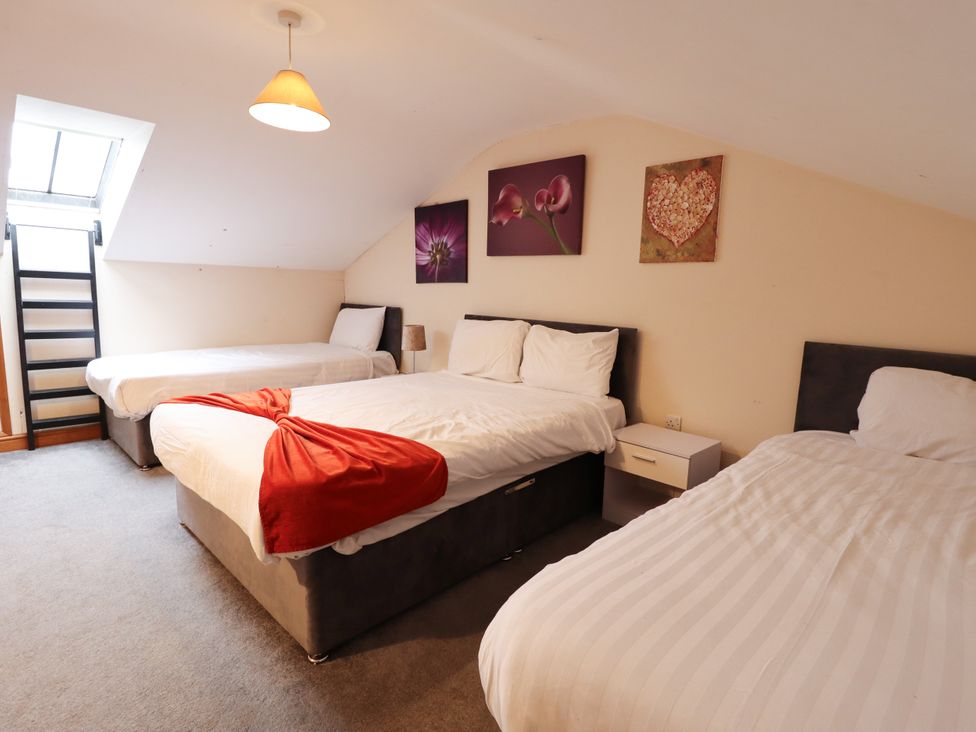 A bedroom with three beds and wall art at Holiday Cottage 3 in Skegness