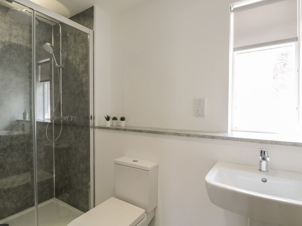 A bathroom with a shower, toilet, and sink at The Cairn 