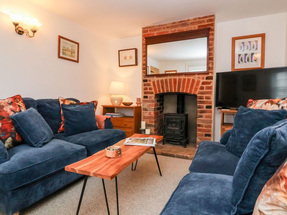 A living room with a fireplace and sofa at Cobblers Cottage Southwold