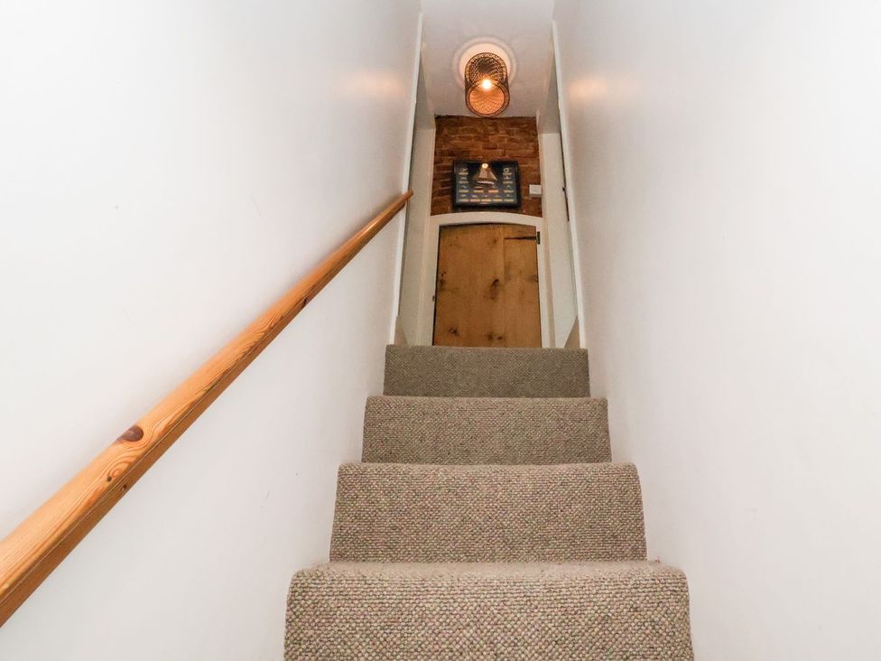 A staircase with a handrail and door at Cobblers Cottage in Southwold