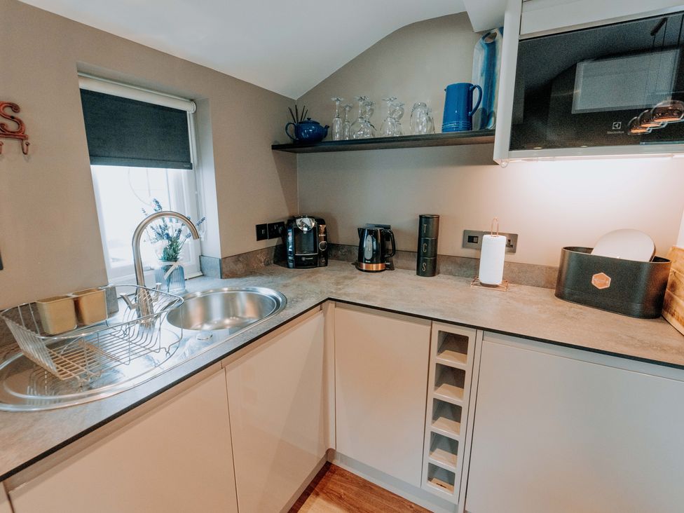 A kitchen with a sink, kettle, coffee machine and dish rack at TyCosy in St Davids