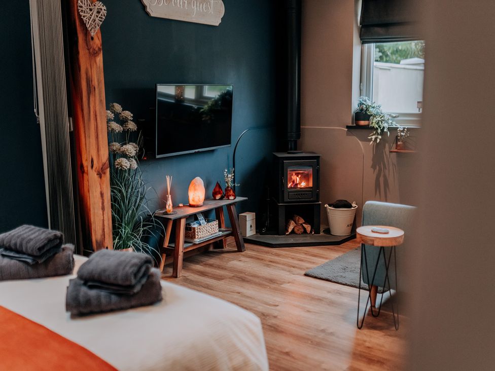 A living room with a television, fireplace, and wooden furniture at TyCosy in St Davids
