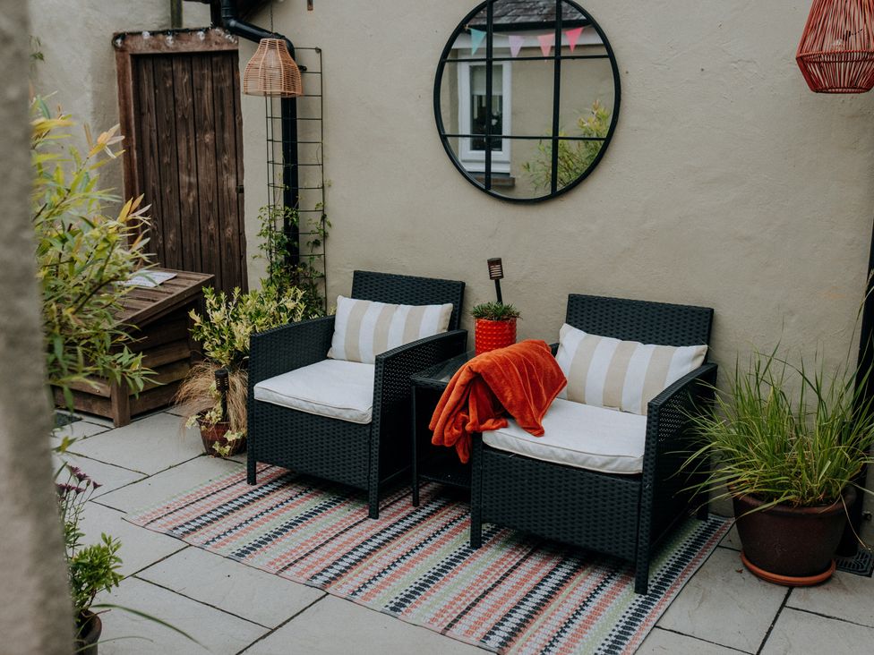 An outdoor seating area with two armchairs and a mirror at TyCosy St Davids