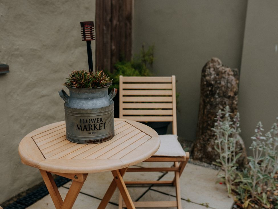 A table and chair with a planter in a garden at TyCosy St Davids